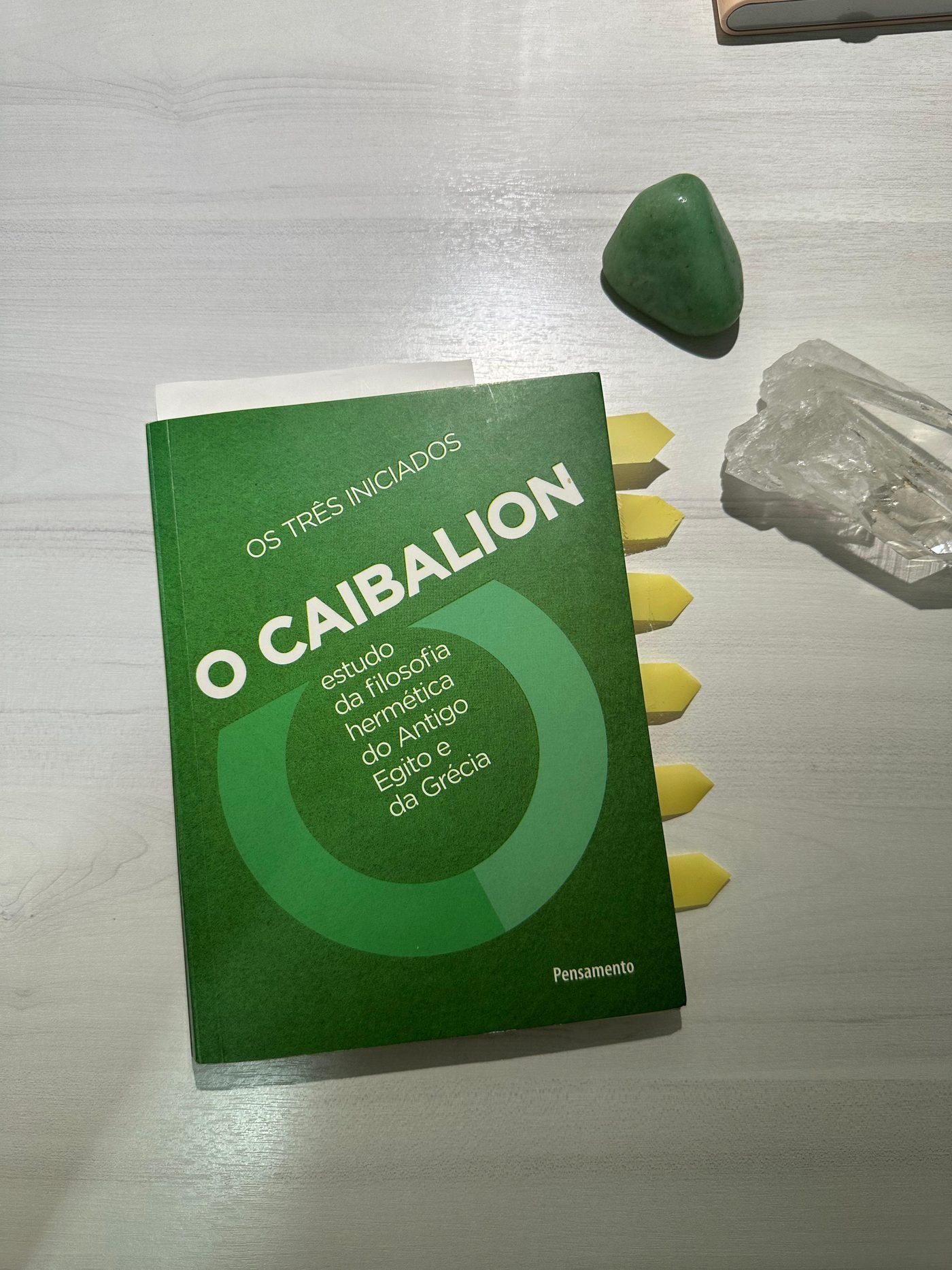 O livro O Caibalion sobre a mesa, ao lado de cristais